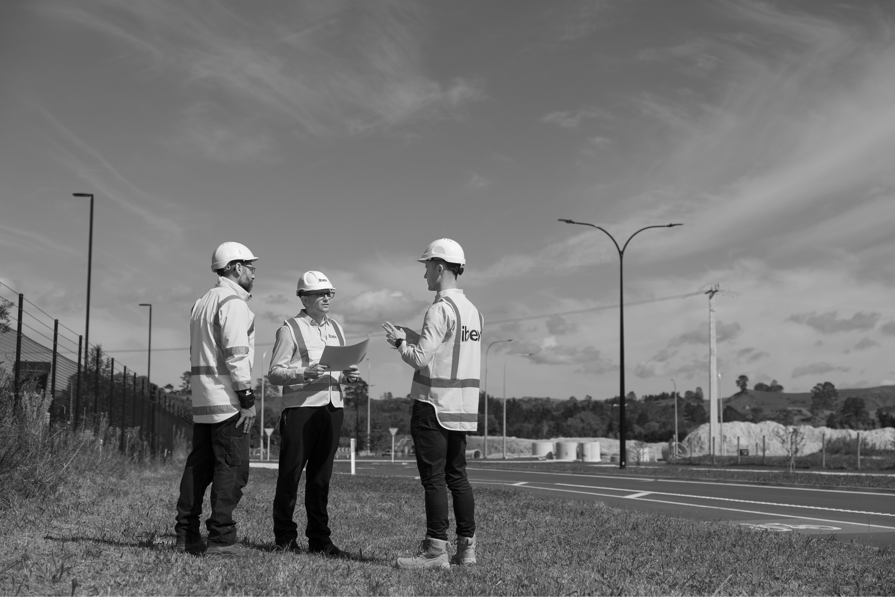 Three construction workers talking on a construction site illuminated by ibex Lighting.