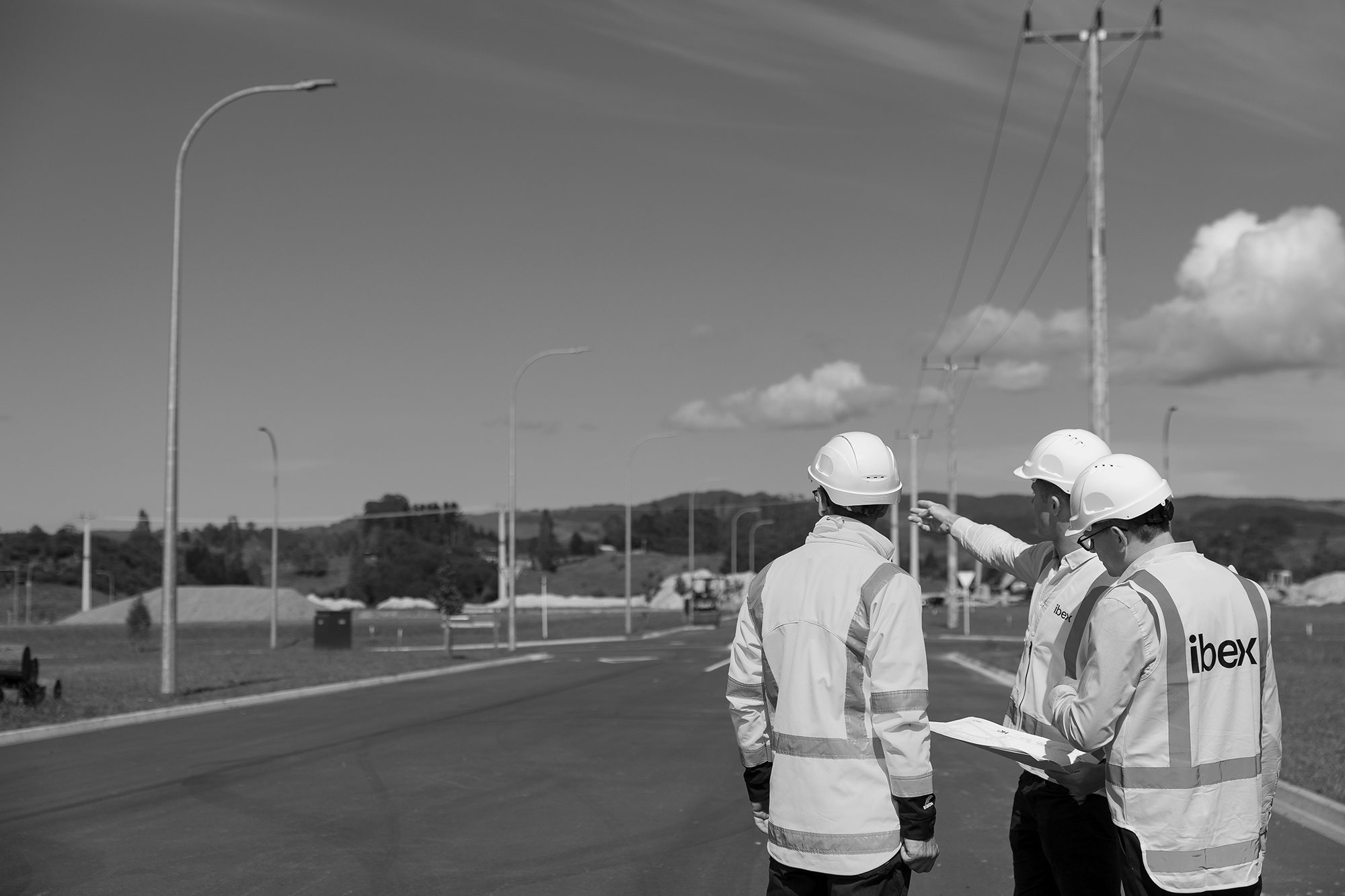 Three construction workers standing on the side of the road, illuminated by ibex lighting.