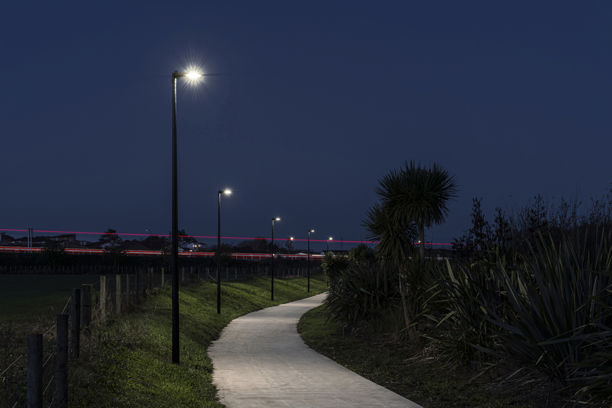 A grassy path at night leading to a grassy field illuminated by ibex Lighting.