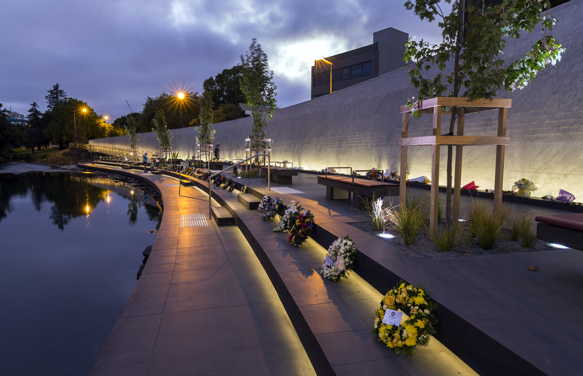 Commemoration night at earthquake memorial wall illuminated by ibex lighting.
