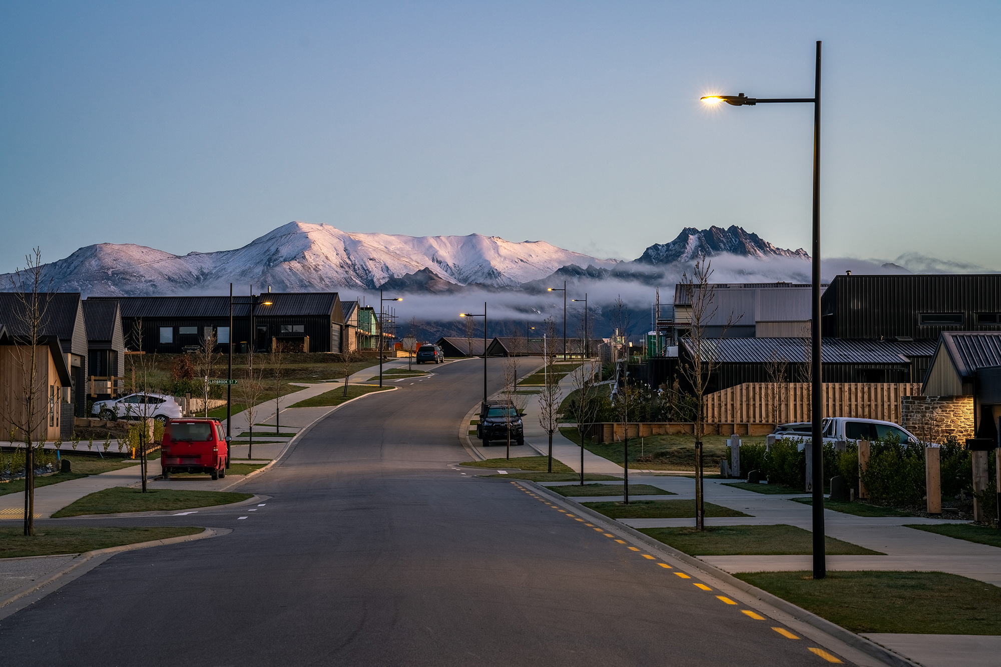 Northlake neighbourhood road at dusk illuminated by ibex lighting solutions with magnificent mountain in the background.