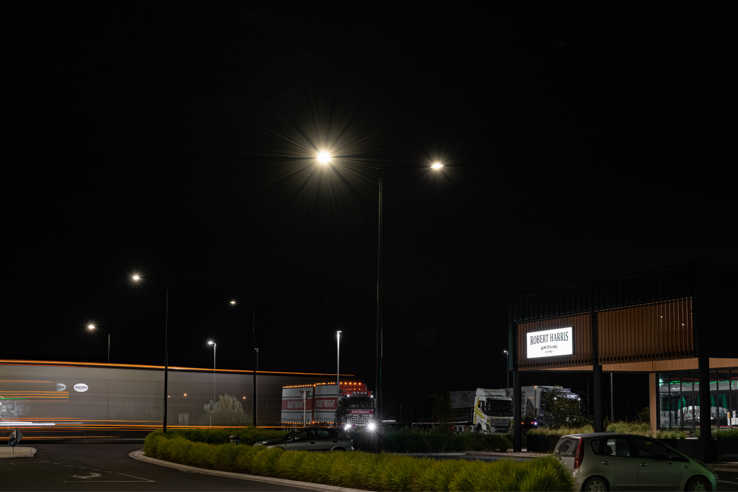 A car is parked in a parking lot at night, illuminated by Ibex Lighting.